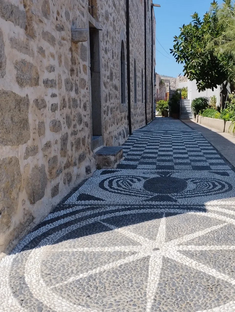 Traditional patterned pebble paving beside a stone building